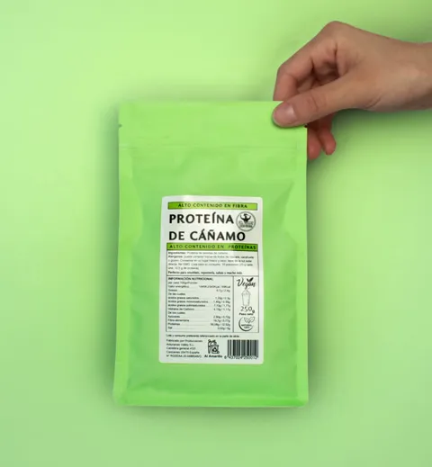 Bolsa de proteína de cáñamo en polvo sostenida con una mano sobre fondo verde lima